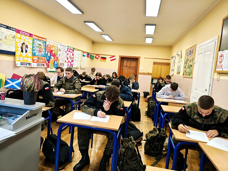 Uczniowie w lawkach na konkursie widok klasy od strony tablicy